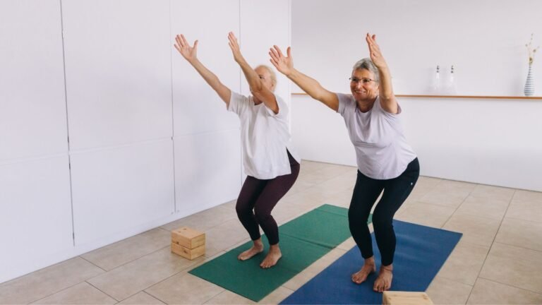 Zwei Frauen machen Balance-Übung im Stehen auf Yoga-Matten