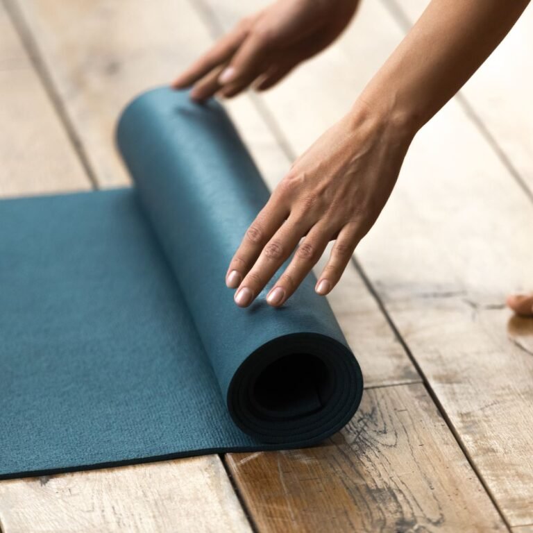 Hände rollen eine Yogamatte zusammen