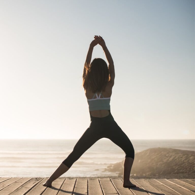 Frau steht in weiter Haltung und streckt die Arme nach oben